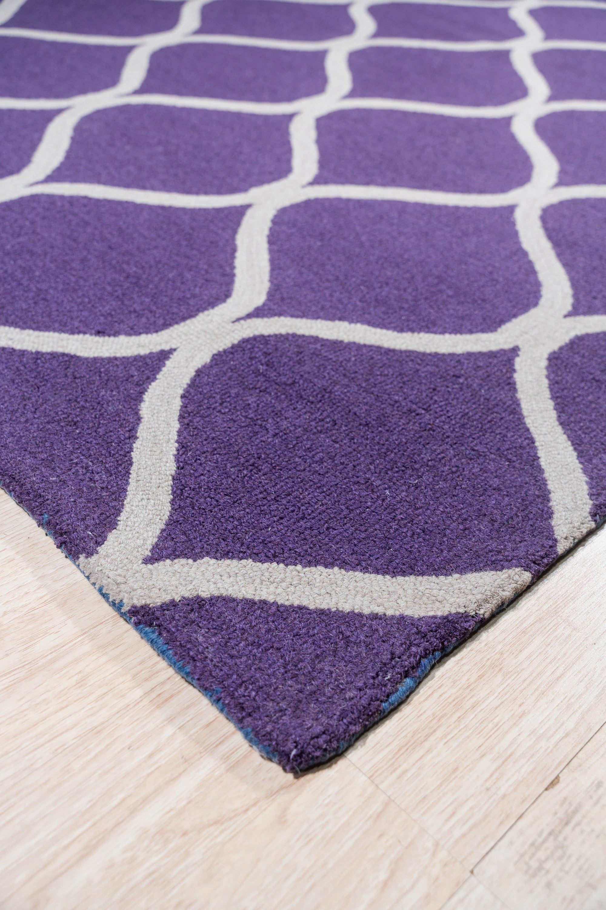Lush Handcrafted Purple Hand Tufted Wool Rug, luxurious deep purple wool pile invites touch. Hand-tufted construction creates a plush texture, seen in a close-up showcasing the rug's craftsmanship.