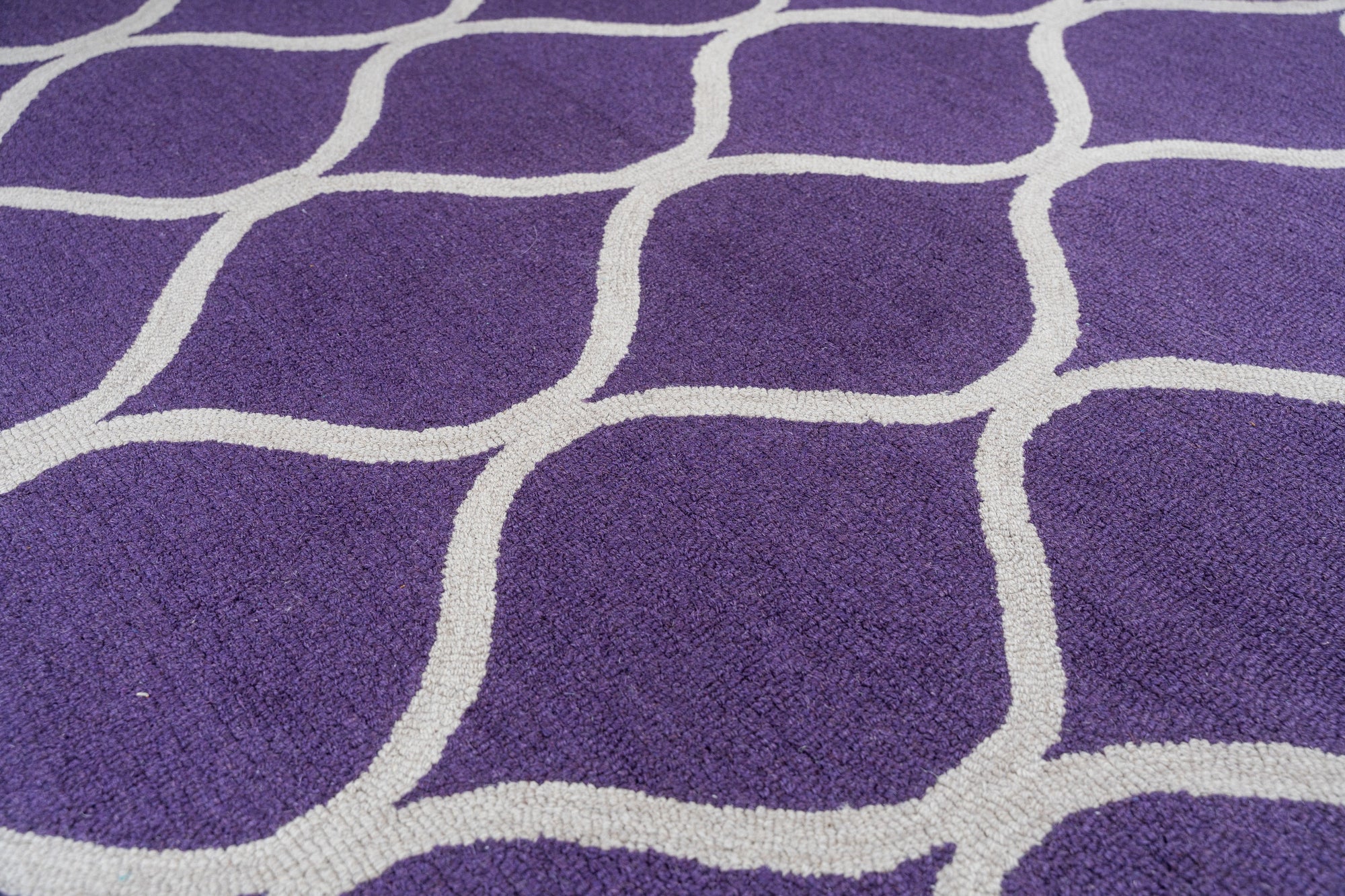 Lush Handcrafted Purple Hand Tufted Wool Rug, a vibrant splash of deep purple wool with a luxuriously plush texture, anchoring a minimalist living room setting.