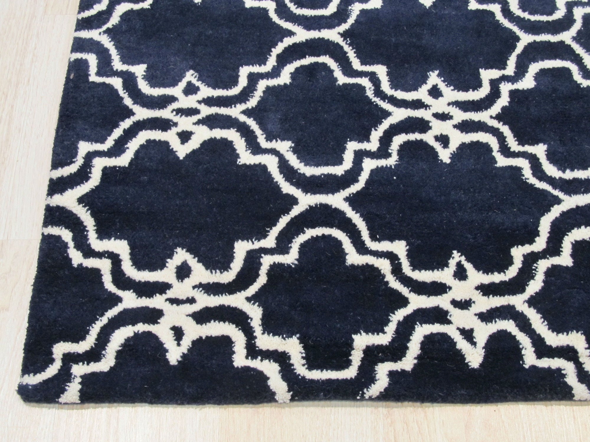 Penelope Moroccan Blue Hand Tufted Wool Rug, features a geometric design with varying shades of blue and cream, hand-tufted wool construction visible in a styled room setting.