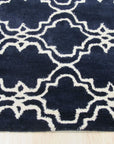 Penelope Moroccan Blue Hand Tufted Wool Rug, features a geometric design with varying shades of blue and cream, hand-tufted wool construction visible in a styled room setting.