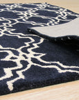 Penelope Moroccan Blue Hand Tufted Wool Rug, showcasing intricate geometric patterns in shades of blue and cream, lending an air of sophisticated comfort to a stylishly decorated living room.