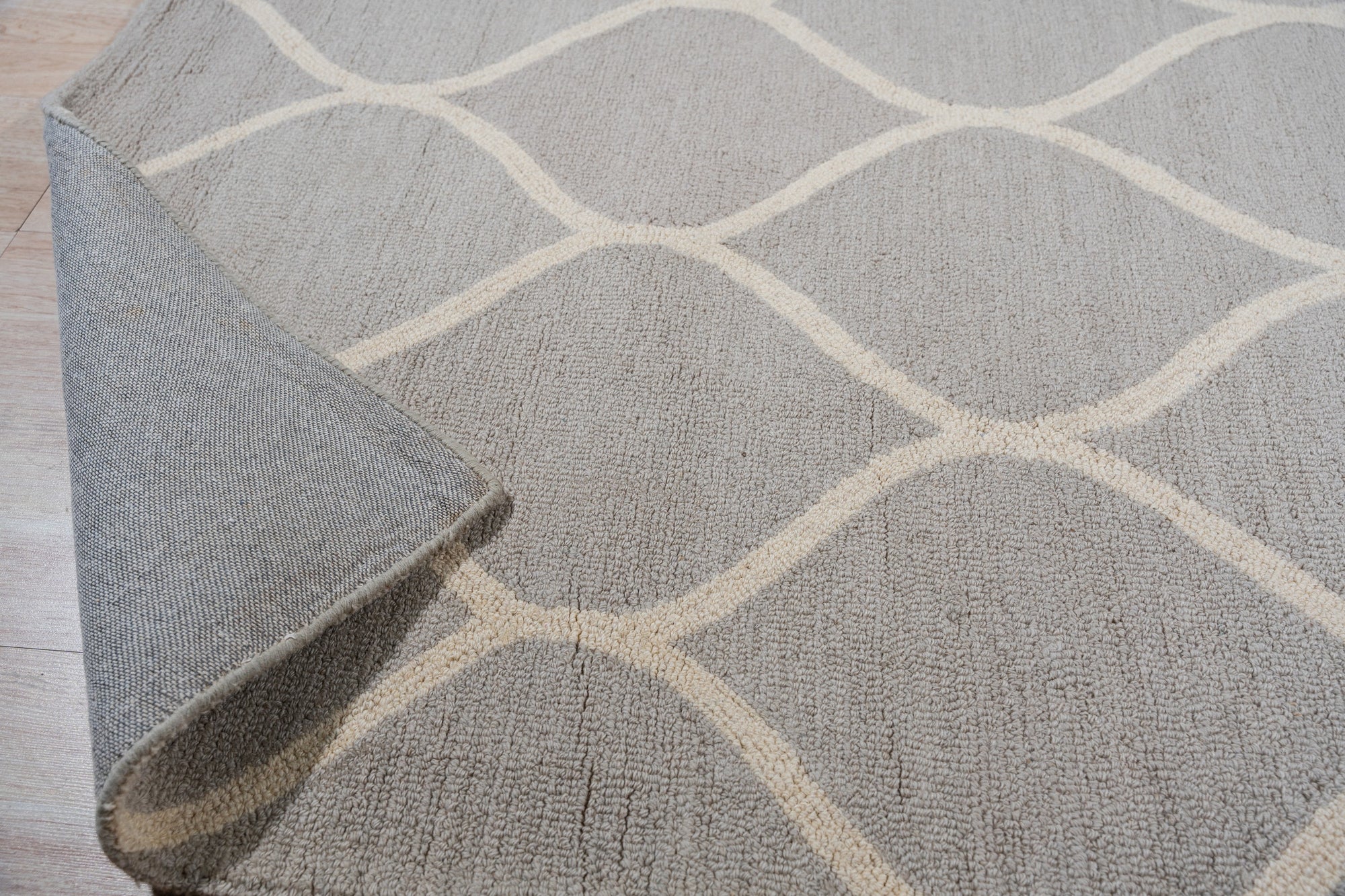 Classic Cozy Light Brown Hand Tufted Wool Rug, a light brown wool rug with a plush, textured surface, rests elegantly on a dark wood floor, suggesting warmth and comfort.