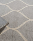 Classic Cozy Light Brown Hand Tufted Wool Rug, a light brown wool rug with a plush, textured surface, rests elegantly on a dark wood floor, suggesting warmth and comfort.