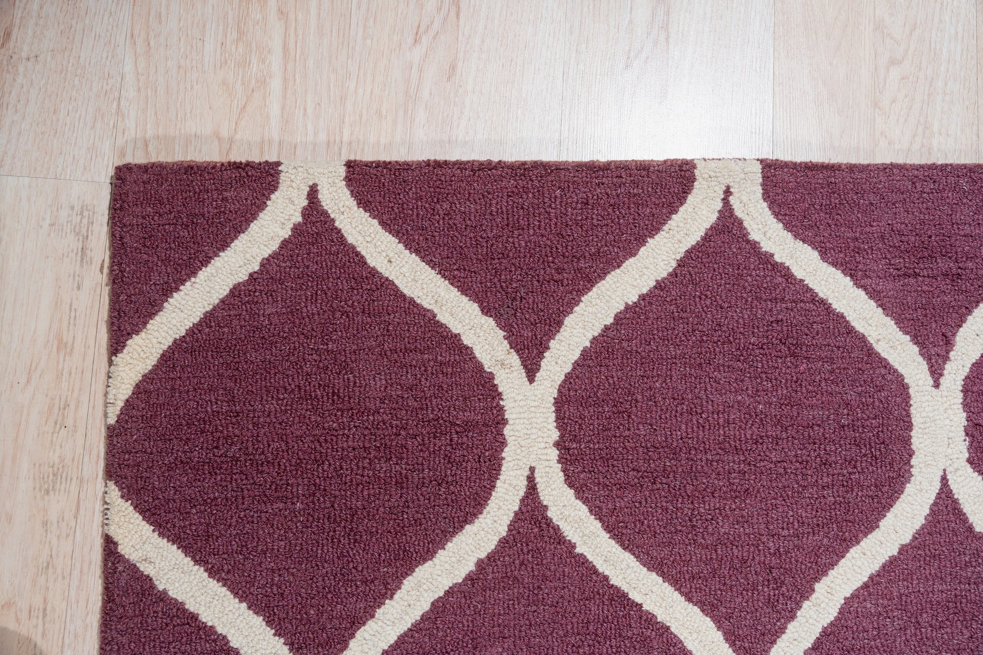 Ava Exquisite Burgundy Hand Tufted Wool Rug, showcasing rich burgundy tones and intricate hand-tufted details, adds warmth and texture to a softly lit room with neutral-toned furniture.