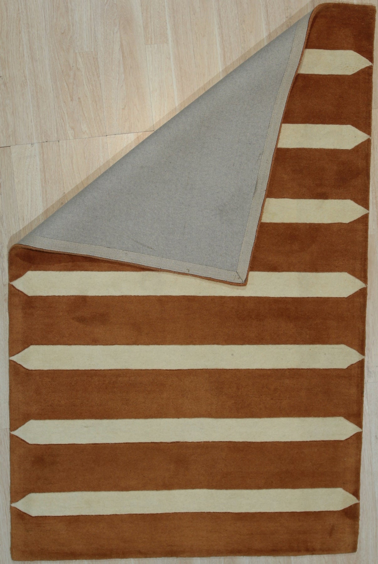 Louie Elena Rust Hand Tufted Wool Rug, its textured surface displaying earthy rust tones and subtle variations in the wool, fills the frame with warmth and inviting comfort.