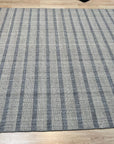 Luxurious Timeless Gray Handmade Wool Rug, soft gray wool pile inviting touch, rests on dark wood flooring, showcasing subtle pattern variations under natural light spilling from a nearby window.