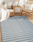 Luxurious Timeless Gray Handmade Wool Rug, soft and inviting, anchors a bright living room. Warm light highlights subtle textures in the hand-knotted wool, contrasting with a modern gray sofa and light wood flooring. A cozy and elegant foundation.
