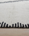 Harlow Moroccan Ivory Hand Knotted Wool Rug, soft ivory wool underfoot, its intricate Moroccan pattern adding subtle texture to a warmly lit room.