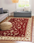 Rustic Agra Red Hand Knotted Wool Rug, showcasing warm reds and intricate patterns, lays grounded against a hardwood floor. The hand-knotted wool construction lends texture and depth to the traditional design, inviting warmth and sophistication into the room.
