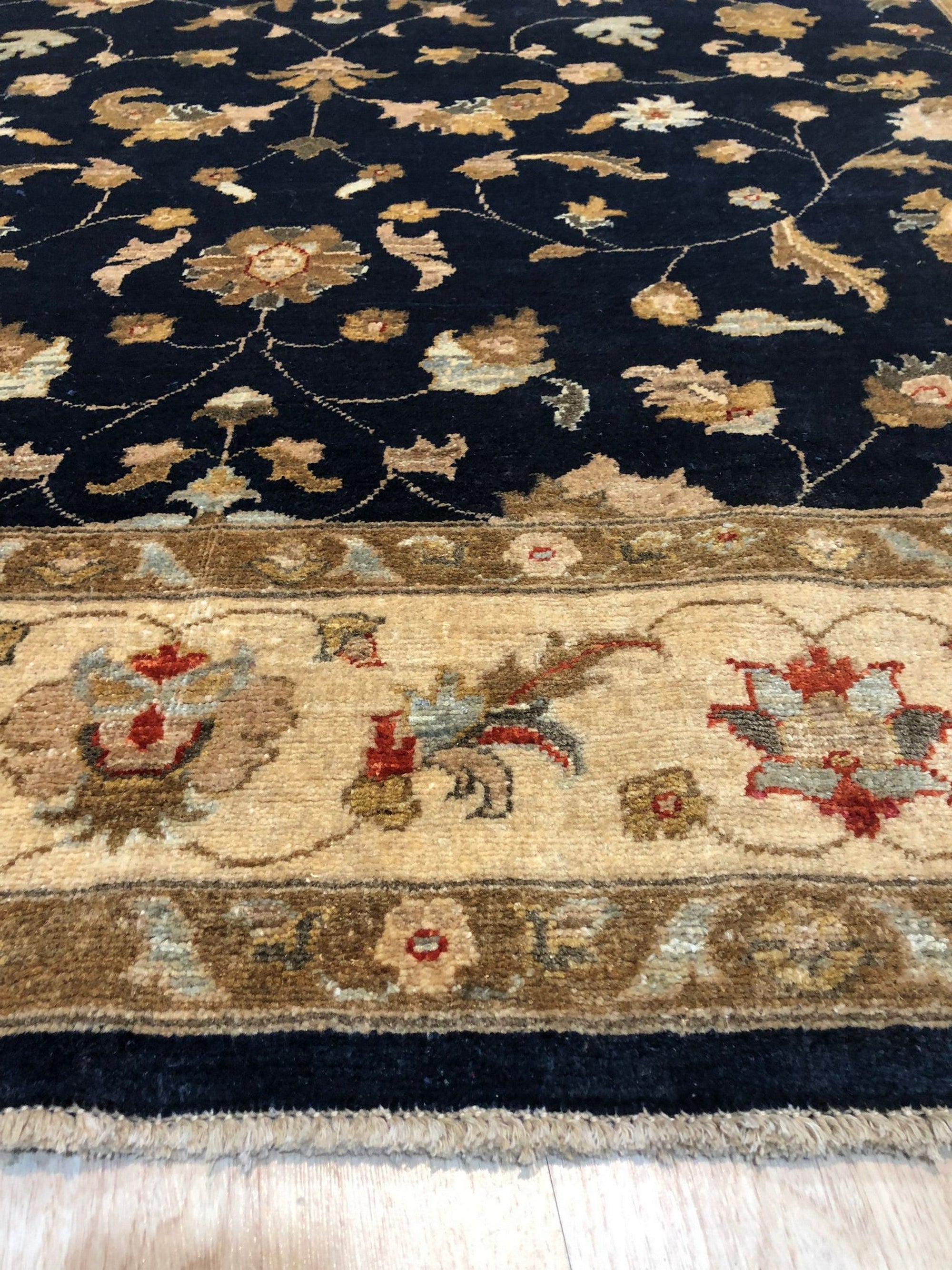Stylish Peshawar Navy Hand Knotted Wool Rug, its rich navy hues and intricate hand-knotted details accent a room setting with warm lighting.