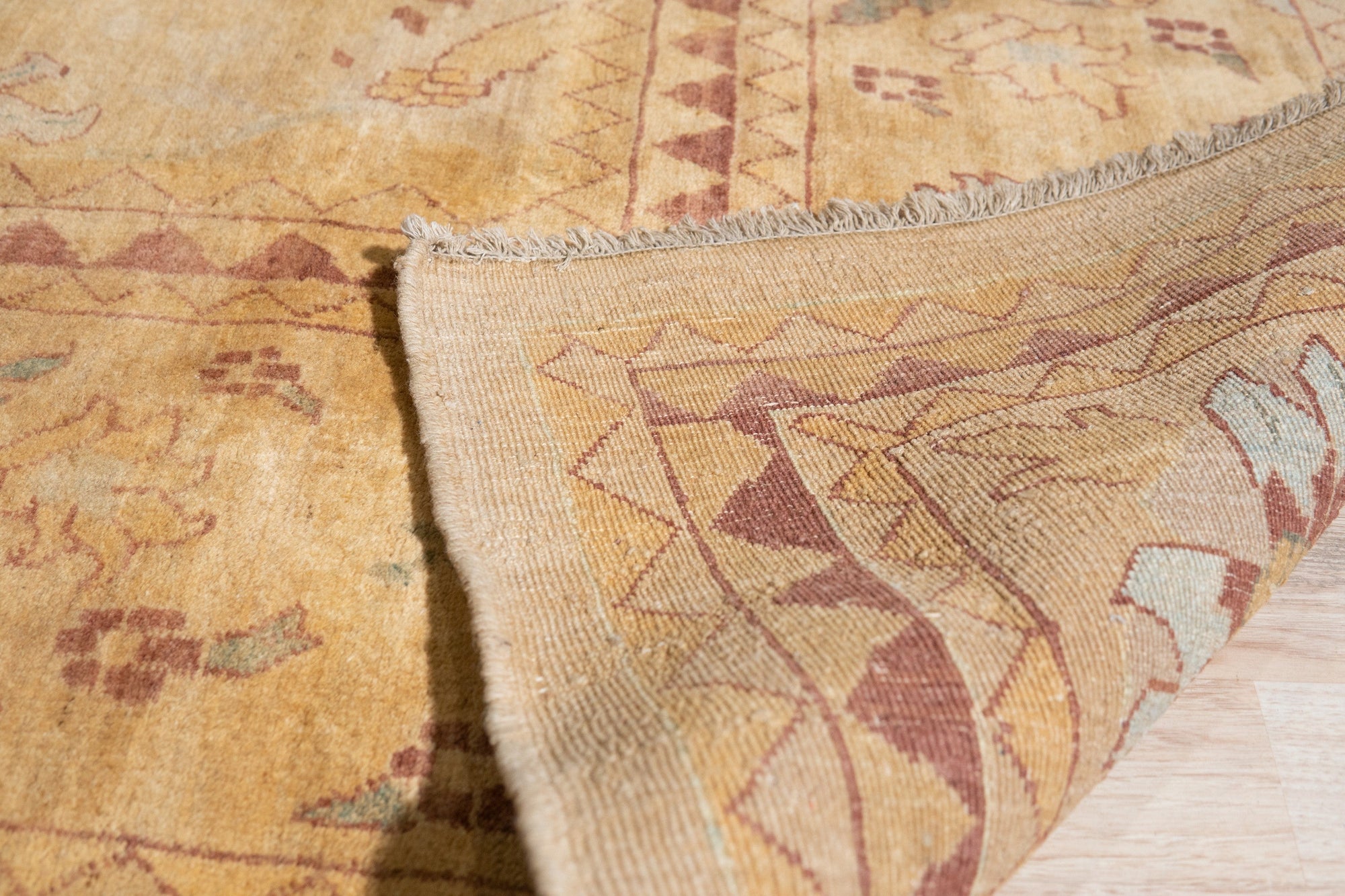 Violet Elegant Beige Hand Knotted Wool Rug, showcasing a detailed floral pattern in beige and violet hues, lies on a light hardwood floor, lending warmth and sophistication to a minimalist space.