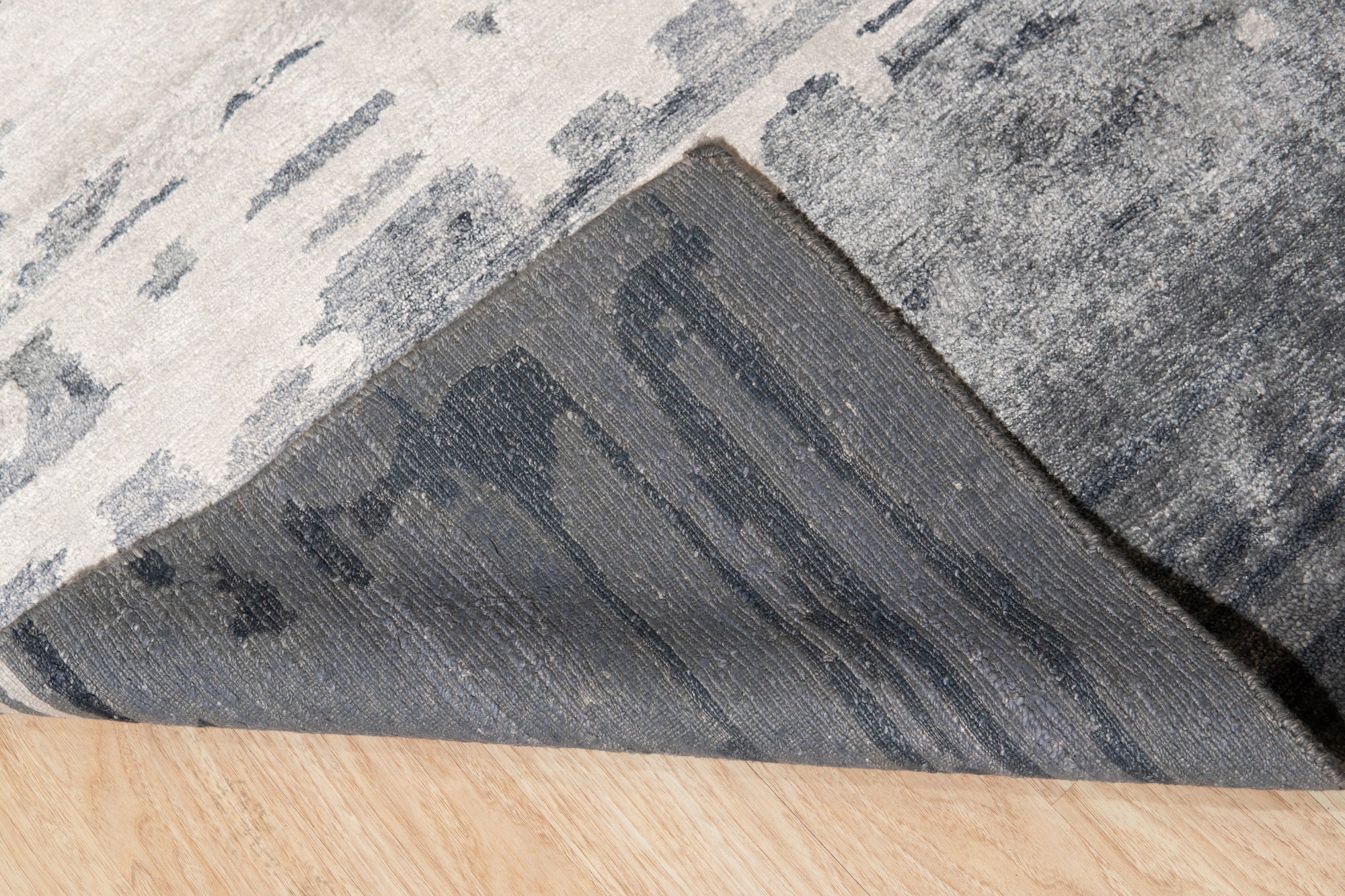 Graceful Classic Gray Hand Knotted Wool & Viscose Rug, blending muted gray tones in a classic, hand-knotted design, graces a modern living space with hardwood floors and subtle natural light.