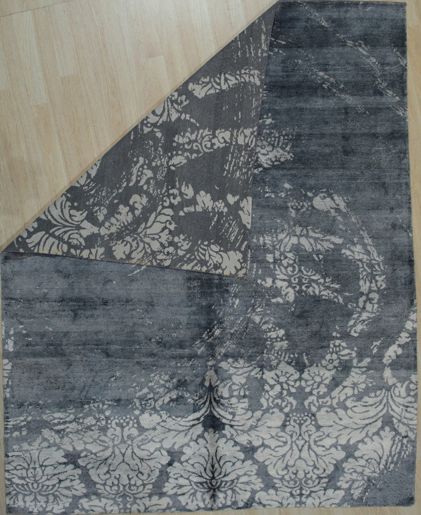 Classic Unique Black Hand Knotted Wool & Bamboo Silk Rug, a luxurious black rug with subtle sheen and intricate, possibly geometric or traditional, design details, displayed on a light surface, emphasizing the rug's texture and craftsmanship.