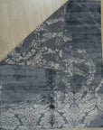 Classic Unique Black Hand Knotted Wool & Bamboo Silk Rug, a luxurious black rug with subtle sheen and intricate, possibly geometric or traditional, design details, displayed on a light surface, emphasizing the rug's texture and craftsmanship.