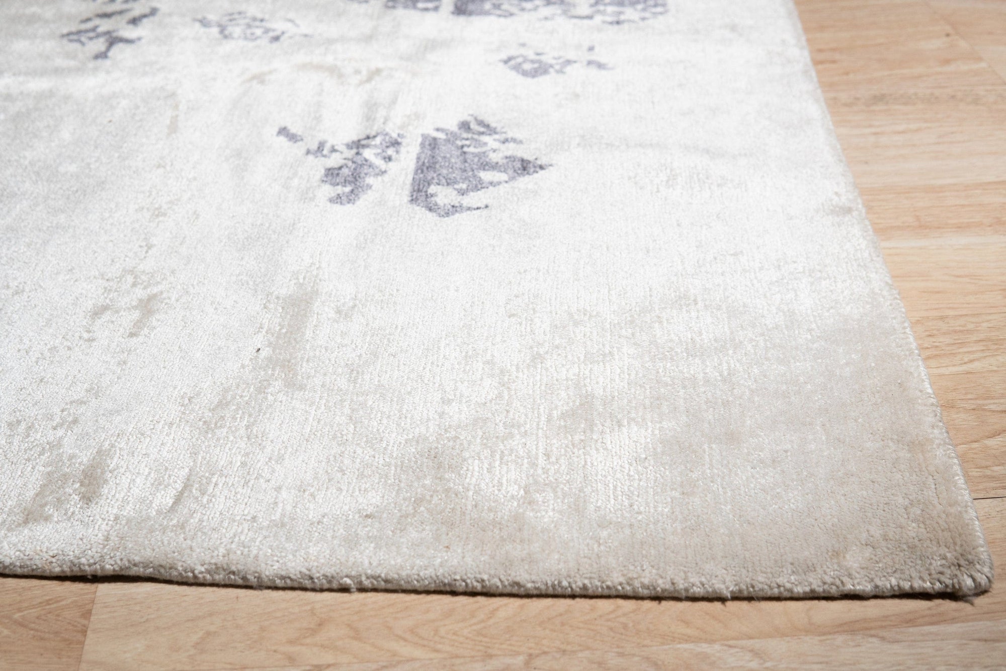 Ella Chic Ivory Hand Knotted Rug, a plush ivory rug with a subtle, textured design, lies elegantly on a light hardwood floor, inviting warmth and sophistication into the room.