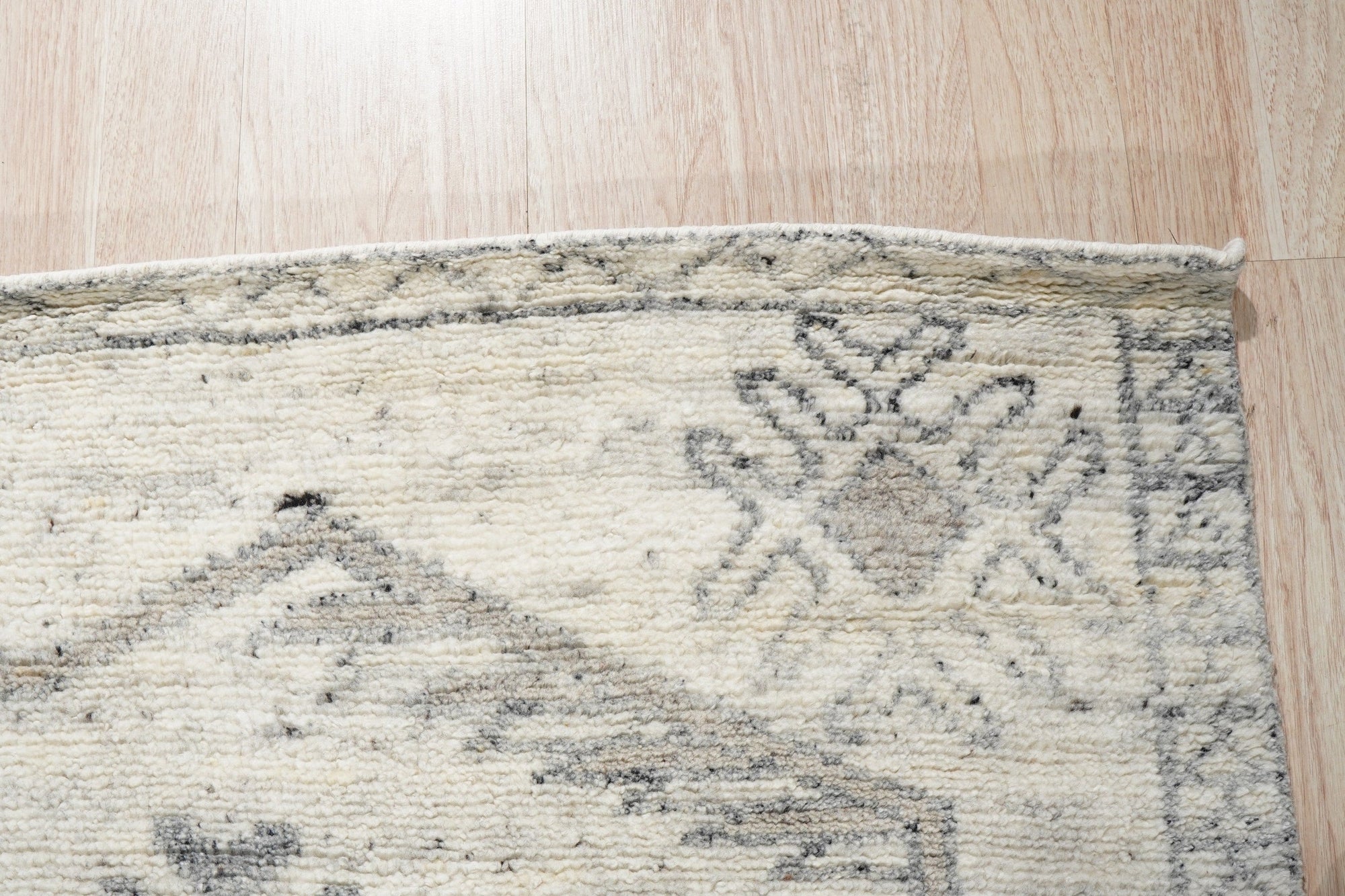 Amara Oushak Ivory Hand Knotted Wool Rug, showcasing intricate floral medallions and subtle geometric patterns in soft ivory tones, complements a naturally lit living space with hardwood floors.