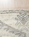 Amara Oushak Ivory Hand Knotted Wool Rug, showcasing intricate floral medallions and subtle geometric patterns in soft ivory tones, complements a naturally lit living space with hardwood floors.