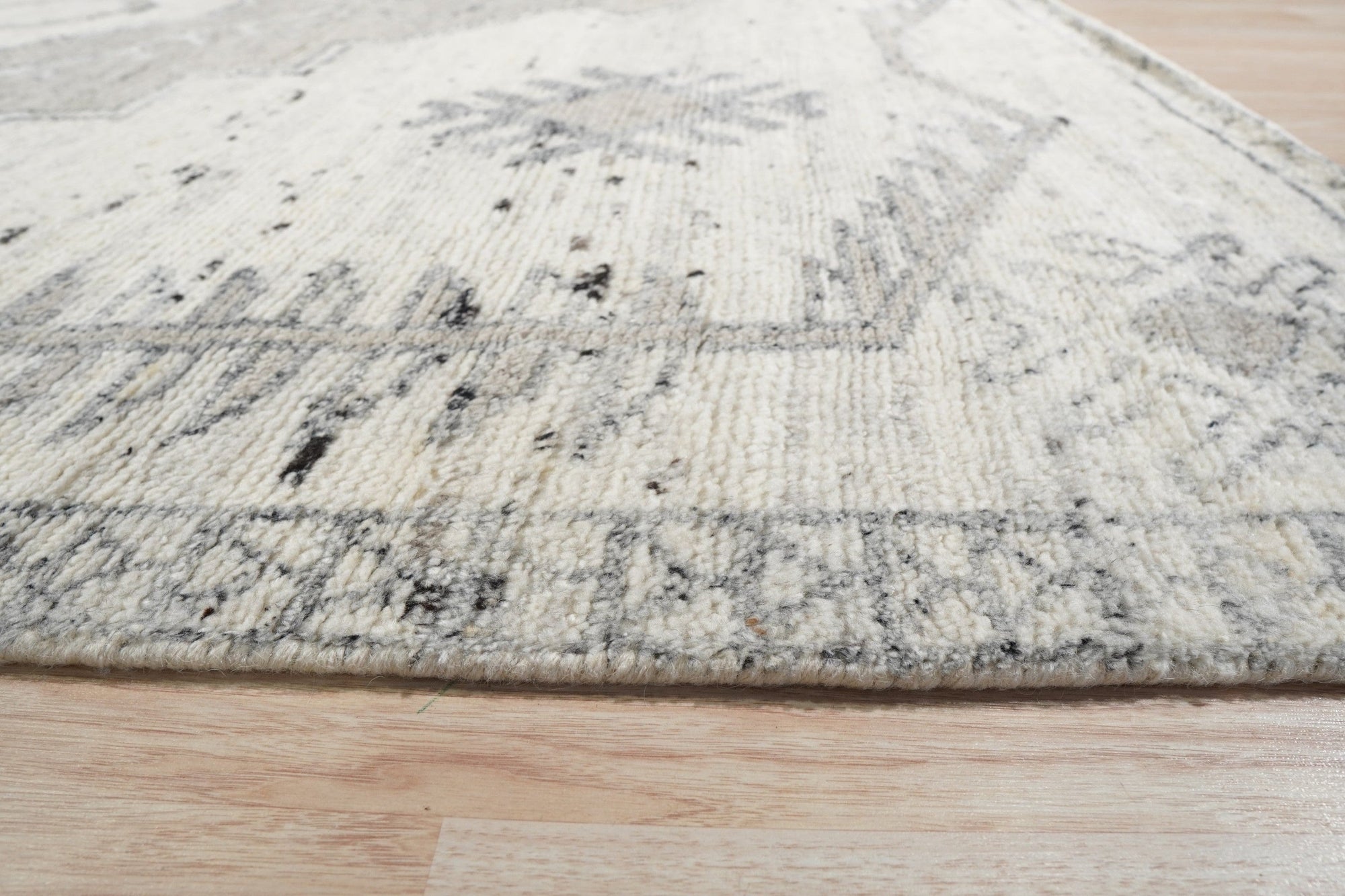 Amara Oushak Ivory Hand Knotted Wool Rug, showcasing intricate floral patterns and soft ivory tones, nestled within a brightly lit living space.
