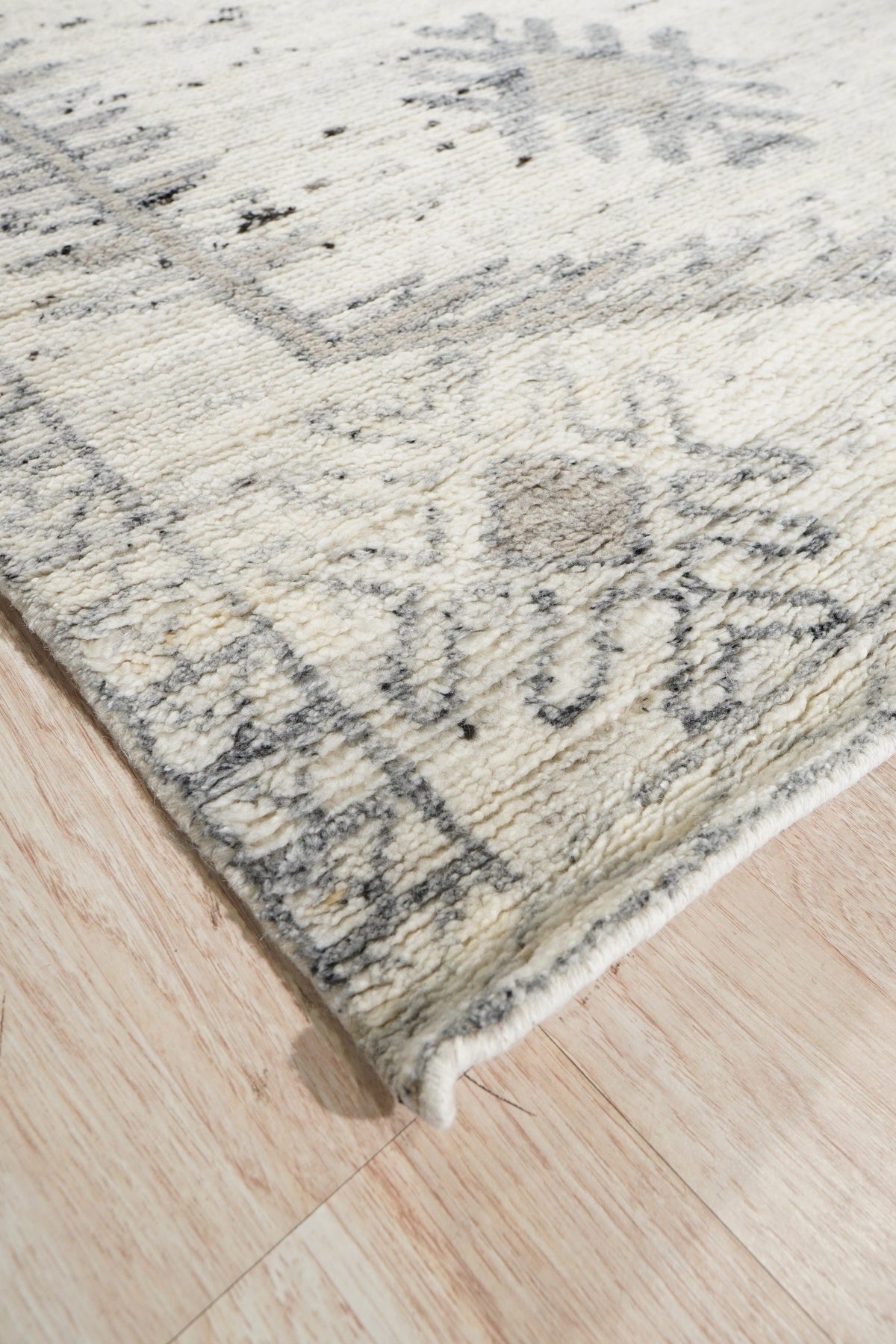 Amara Oushak Ivory Hand Knotted Wool Rug, its intricate floral pattern in soft ivory and muted earth tones, laid on a light wood floor under warm, natural light.