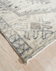 Amara Oushak Ivory Hand Knotted Wool Rug, its intricate floral pattern in soft ivory and muted earth tones, laid on a light wood floor under warm, natural light.