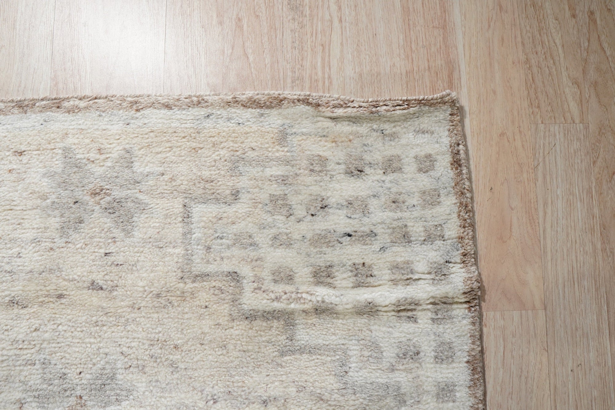 Talia Oushak Ivory Hand Knotted Wool Rug, a richly textured ivory wool rug with a classic Oushak design, lies gracefully on a hardwood floor, its intricate patterns adding warmth and elegance to the room.