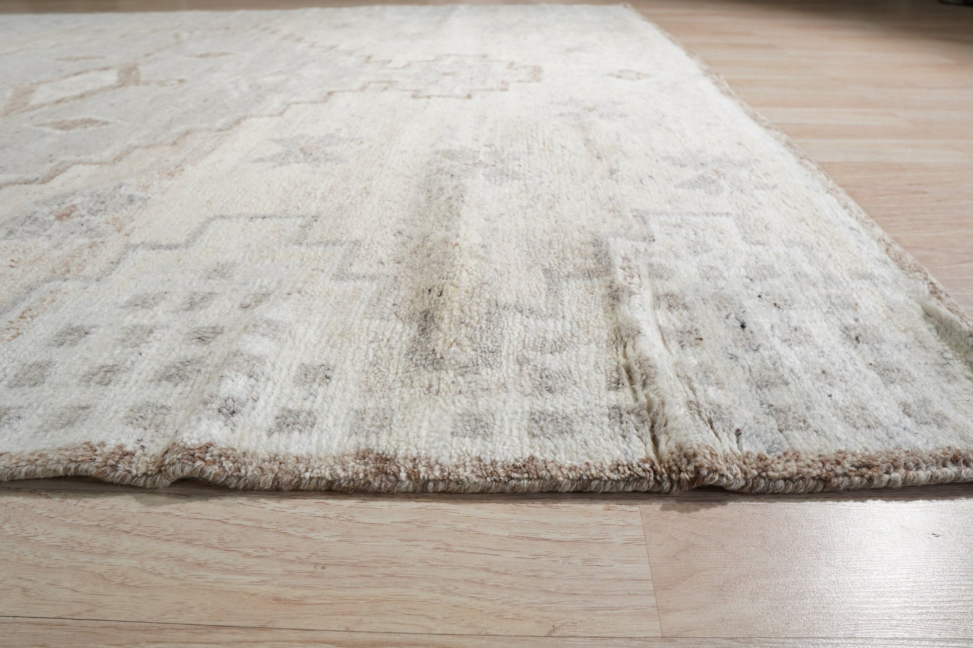 Talia Oushak Ivory Hand Knotted Wool Rug, its intricate floral medallions and soft ivory hues lending warmth to a bright, modern living space with light wood floors.