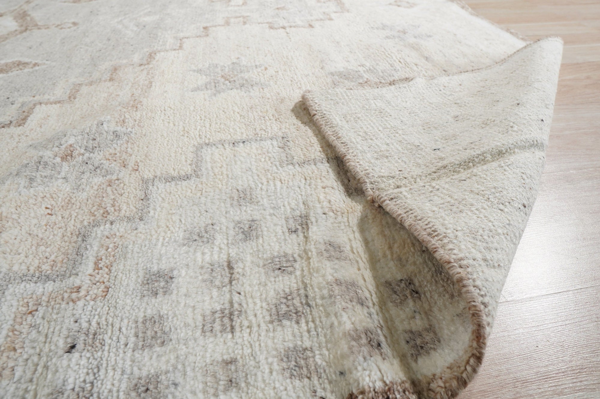 Given the image position is 6, here's the alt text:
 
 Talia Oushak Ivory Hand Knotted Wool Rug, showcasing its intricate floral design and soft ivory tones in a warmly lit room, complementing a modern interior.
