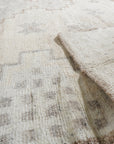 Given the image position is 6, here's the alt text:
Talia Oushak Ivory Hand Knotted Wool Rug, showcasing its intricate floral design and soft ivory tones in a warmly lit room, complementing a modern interior.