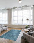 Hand-knotted silk rug, Jade Elegant Blue, shimmering with intricate details, catches light in a close-up view. Threads of deep blues and subtle greens blend seamlessly, demonstrating the rug's luxurious texture and artisan craftsmanship.