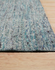 Jade Elegant Blue Hand Knotted Silk Rug, showcasing intricate patterns and shimmering silk fibers, lies flat on a light surface, its rich blue hues and delicate knotting details clearly visible.