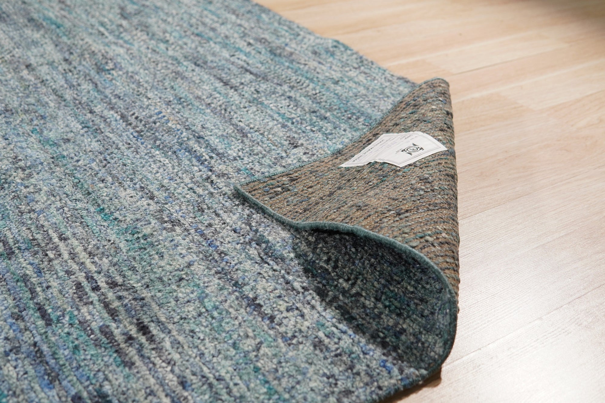 Jade Elegant Blue Hand Knotted Silk Rug, its deep blues and intricate patterns unfolding across a luxurious, hand-knotted silk surface, displayed in a staged interior setting.