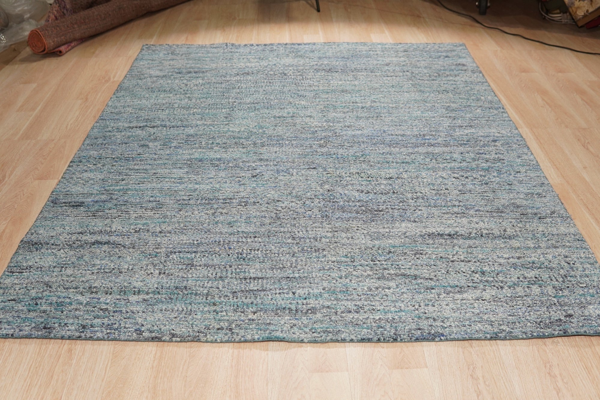 Jade Elegant Blue Hand Knotted Silk Rug, displaying intricate patterns and rich blue hues, laying flat to showcase its luxurious silk texture and hand-knotted construction.