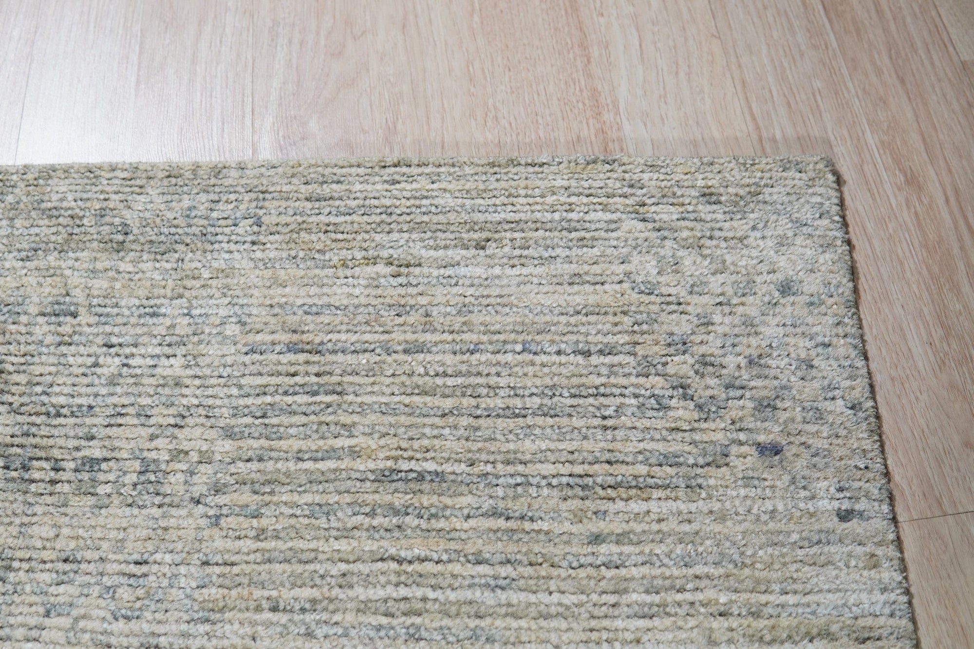 Luna Chloe Green Hand Knotted Silk Rug displayed on a light wood floor. Silk sheen highlights subtle variations in the green and neutral tones of the hand-knotted design.