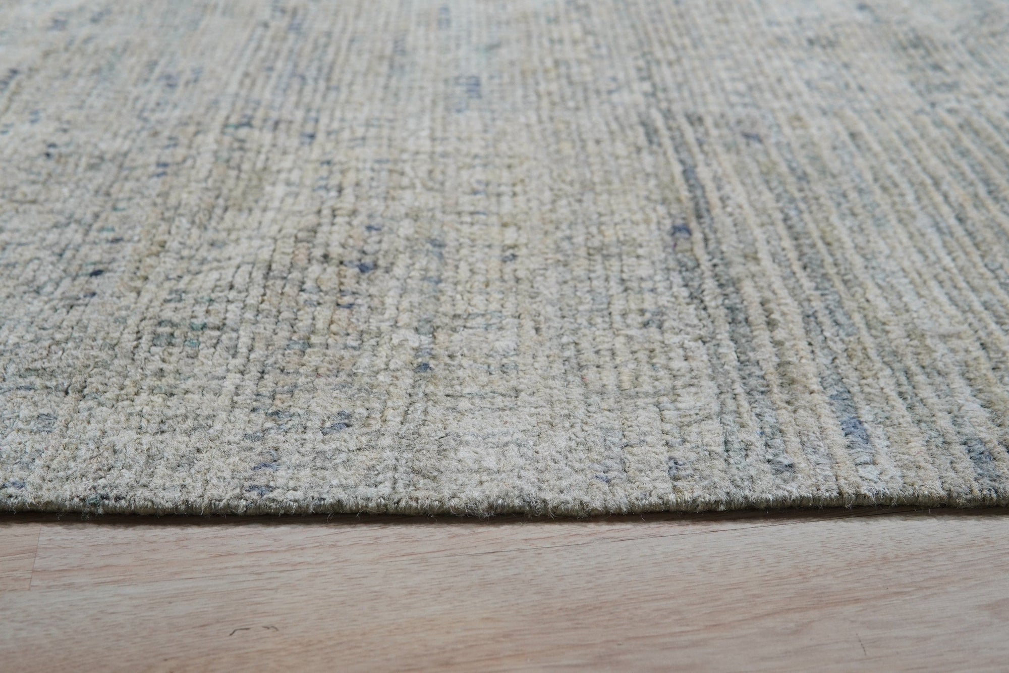 Luna Chloe Green Hand Knotted Silk Rug, shimmering with a soft, muted green hue, displayed in a warmly lit interior setting suggesting sophisticated comfort.