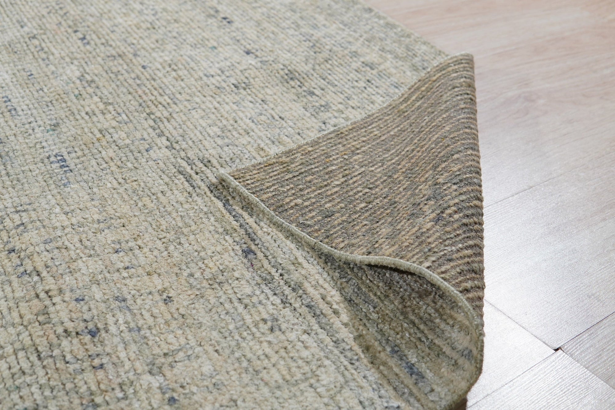 Luna Chloe Green Hand Knotted Silk Rug, showcasing its subtle variations in green tone and delicate, luminous sheen under warm lighting. The hand-knotted texture is visible, adding depth and richness to the rug's surface.