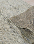 Luna Chloe Green Hand Knotted Silk Rug, showcasing its subtle variations in green tone and delicate, luminous sheen under warm lighting. The hand-knotted texture is visible, adding depth and richness to the rug's surface.