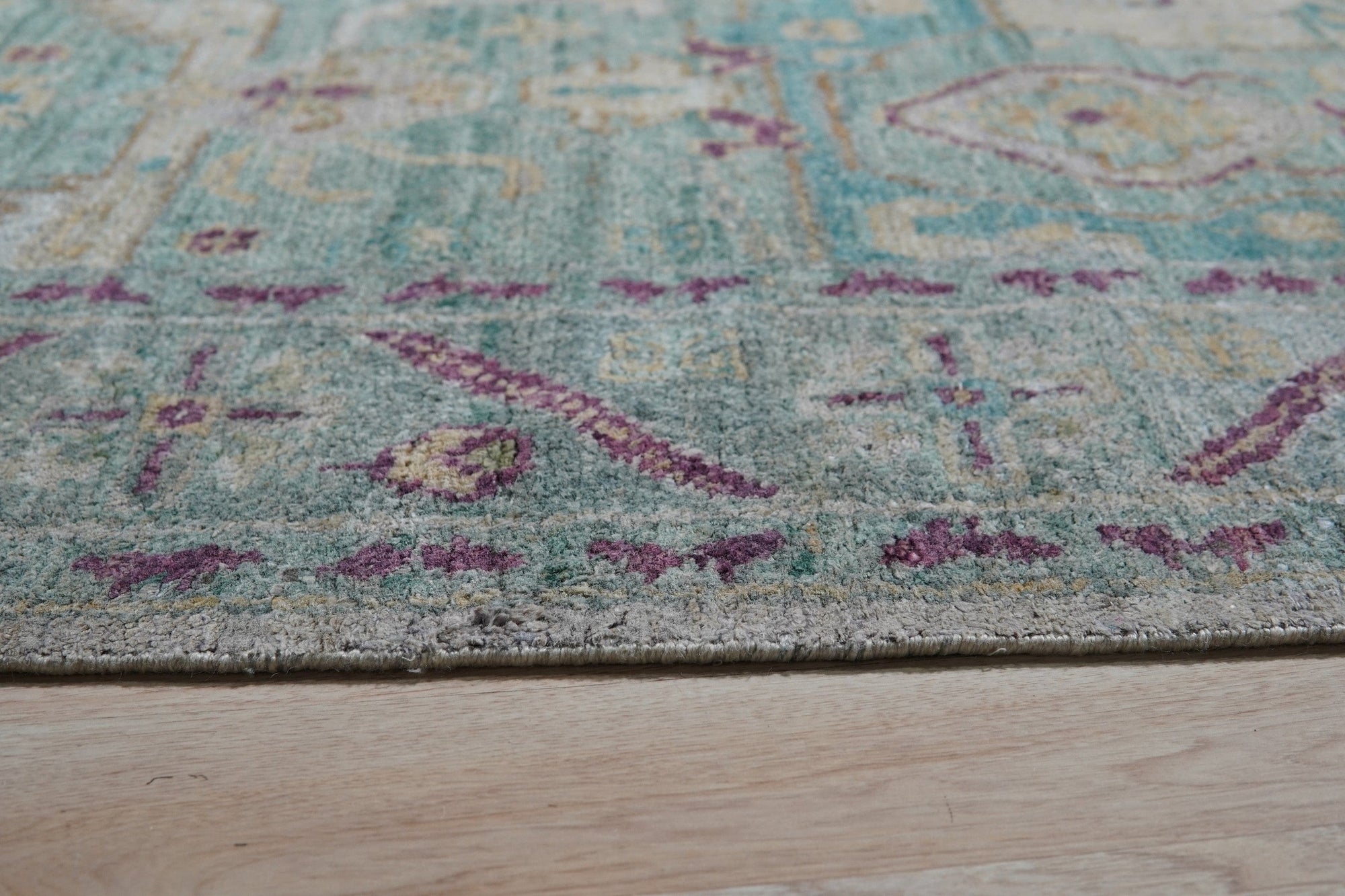 Celia Modern Green Hand Knotted Silk Rug, its luxurious sheen and intricate knotting evident, displayed in a bright, contemporary living room setting.