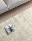 Talia Artisan Gray Handmade Rug, woven with subtle textures, rests on a light wooden floor beside a modern gray sofa, its gray hues complementing the minimalist setting.