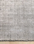 Talia Artisan Gray Handmade Rug displayed in a bright living room setting, its neutral gray tones complementing a modern sofa and wooden coffee table.