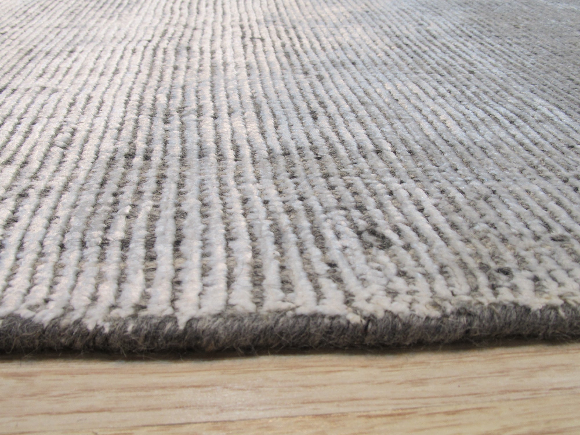 Talia Artisan Gray Handmade Rug, blends seamlessly into a bright living room with neutral furniture; handcrafted rug with a subtle, textured gray pattern anchors the space, adding warmth and sophisticated style.
