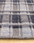 Radiant Tessa Blue Handmade Bamboo Silk Rug, shimmering in cool blues and subtle silvers, lies gracefully on a polished floor, its delicate bamboo silk weave catching the light.