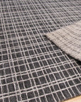 Penelope Isla Gray Handmade Bamboo Silk Rug, seen in a styled room setting. The rug's subtle gray tones and shimmering bamboo silk construction add a touch of luxury beneath modern furniture.