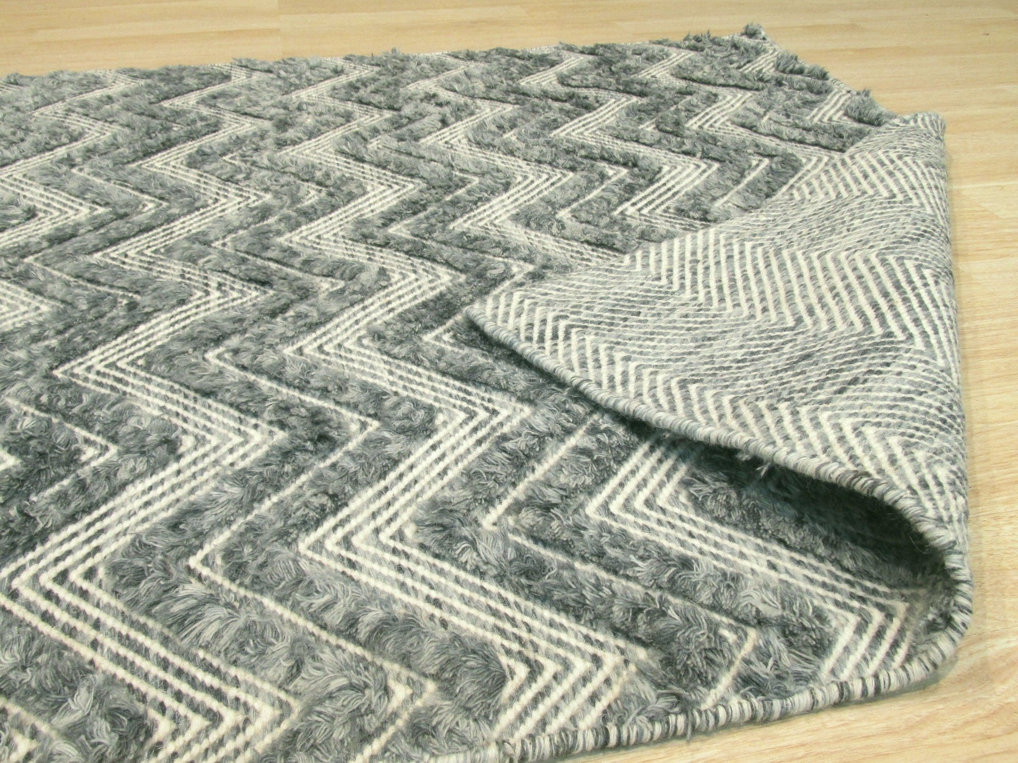 Charming Trara Green Handmade Wool Rug displayed within a bright living space, its green hue complementing the natural light. Wool rug showcases a subtle, textured design adding warmth and character to the room's decor.