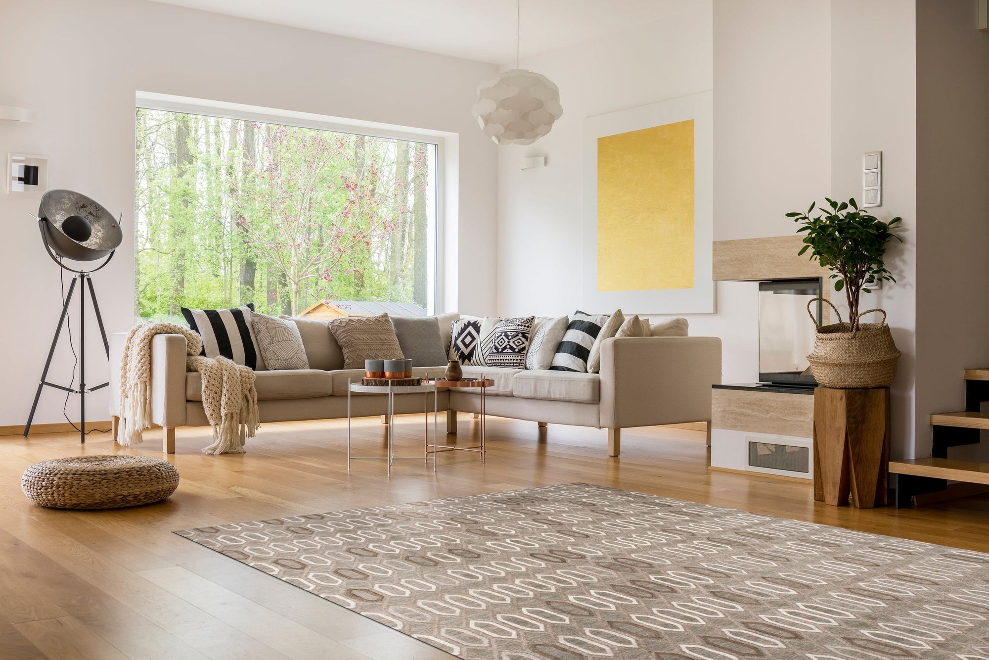 Lila Trellis Gray Nan Rug, a soft gray rug with a repeating trellis pattern, lies on a light hardwood floor, suggesting a cozy and stylish living space.