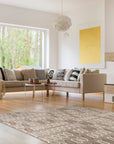 Lila Trellis Gray Nan Rug, a soft gray rug with a repeating trellis pattern, lies on a light hardwood floor, suggesting a cozy and stylish living space.