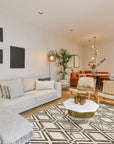 Chic Rhea Gray Hand Knotted Wool Rug, its soft gray tones and hand-knotted texture grounding a modern living space with a mid-century armchair and natural light.