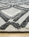 Chic Rhea Gray Hand Knotted Wool Rug, blending soft grays in a subtly textured field, lies anchored in a well-lit living space, showcasing its intricate hand-knotted construction and elegant design.