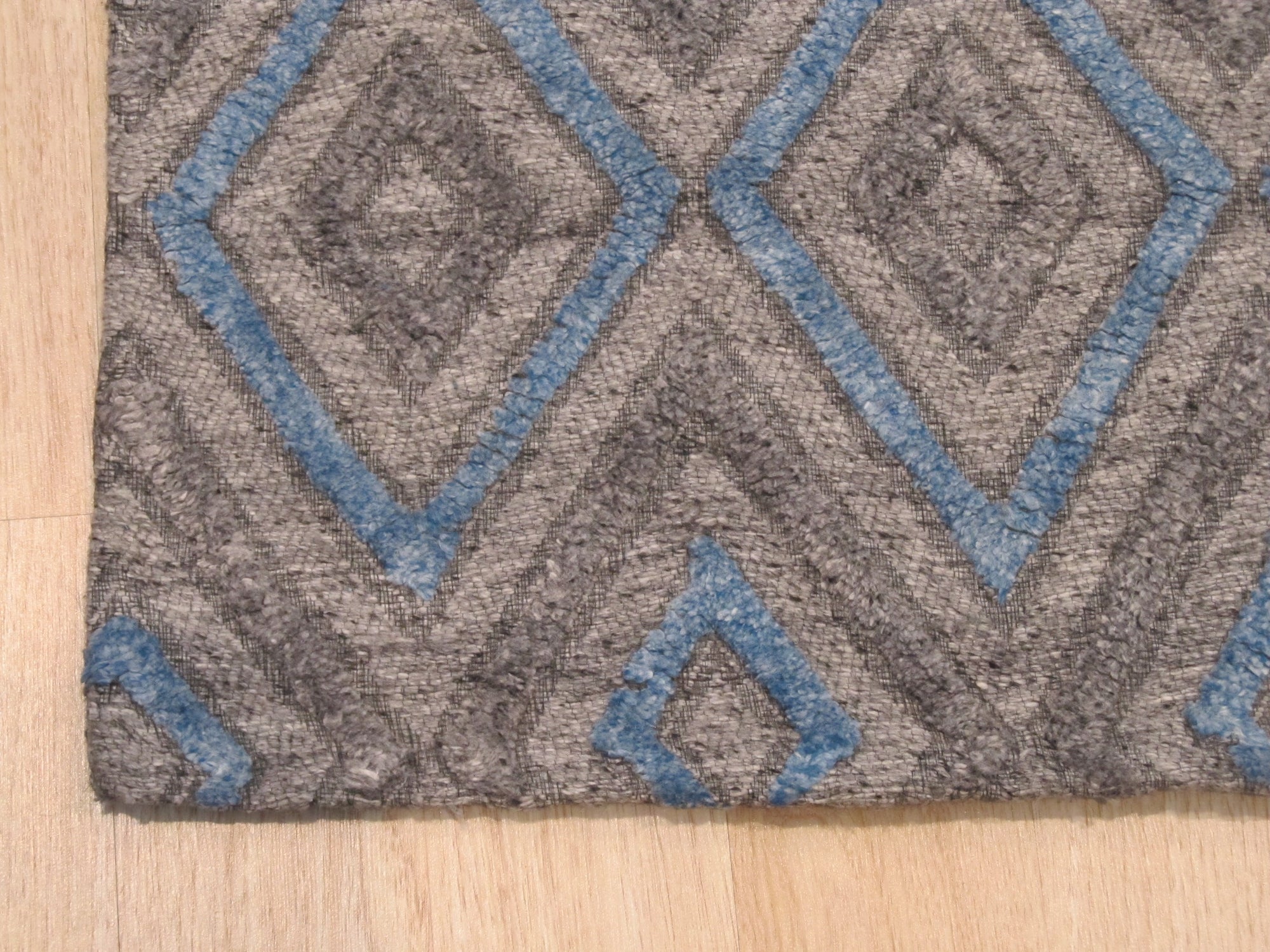 Timeless Trellis Gray Hand Knotted Wool & Viscose Rug, a luxurious gray rug with an elegant trellis design, displayed in a bright, modern living room setting with light wood furniture.