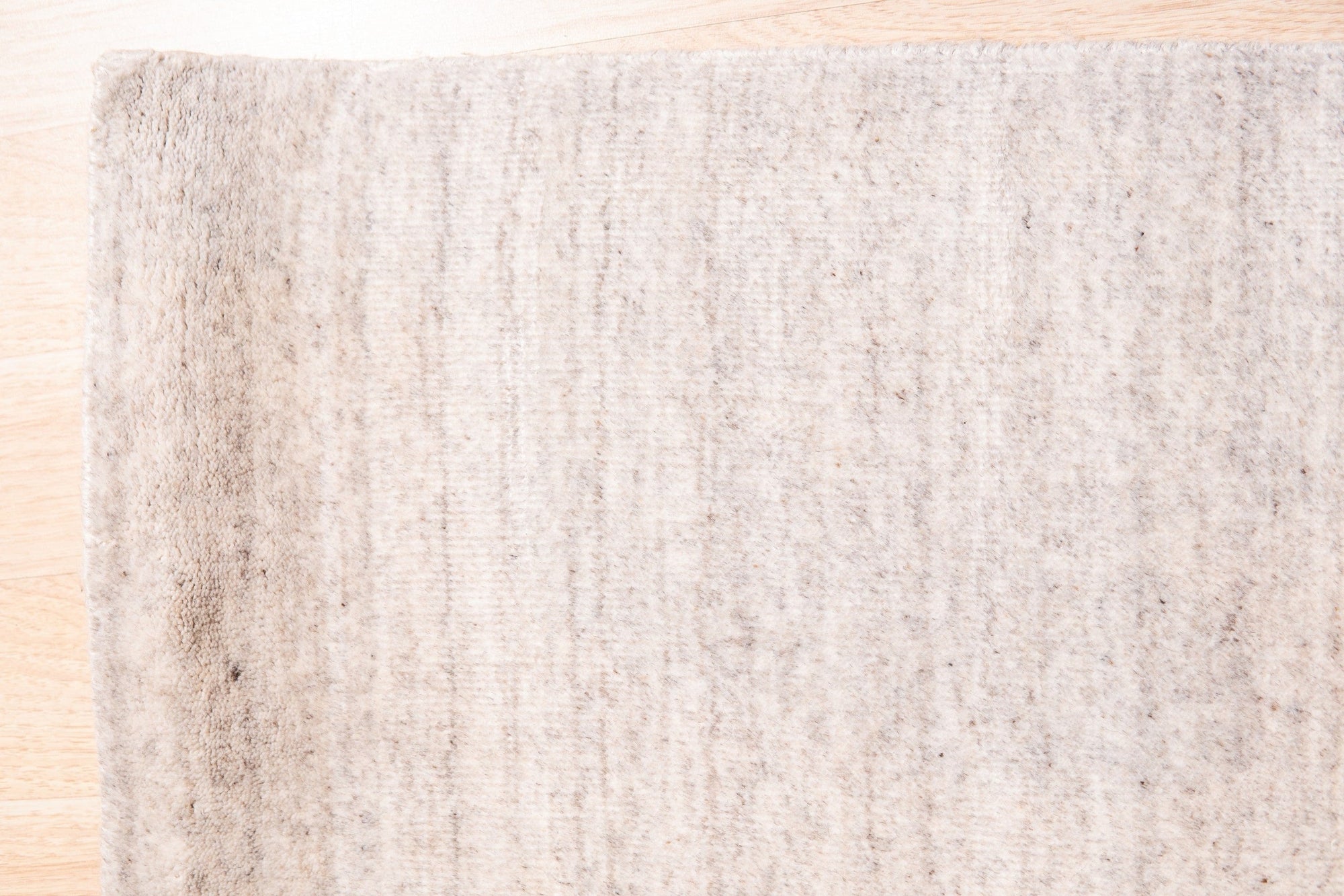 Maya Unique Beige Handmade Wool & Viscose Rug, displaying subtle variations in beige tones and textures, hand-loomed with wool and viscose, grounding a casually elegant room with natural light.