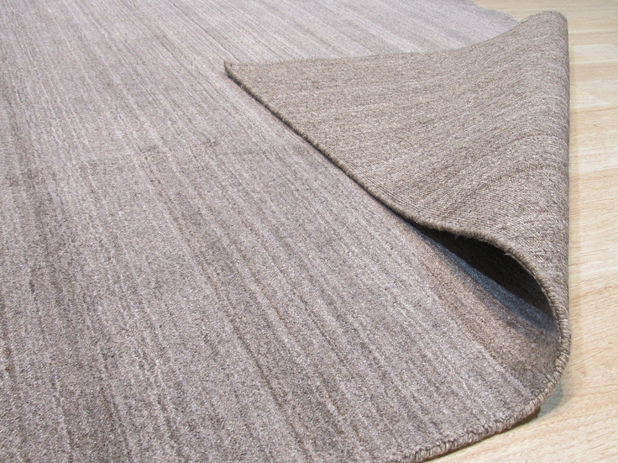 Louie Isla Brown Handmade Wool & Viscose Rug, showcasing a subtle, textured pattern in warm brown tones, hinting at luxurious softness and intricate hand-woven construction.